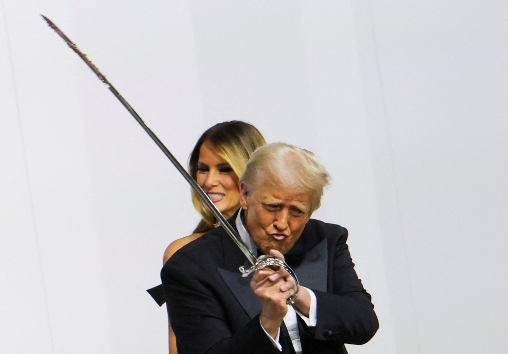 US President Donald Trump gestures while holding a sword, near first lady Melania Trump, as they attend the Commander in Chief Ball in honour of his inauguration in Washington, US, on January 20, 2025. — Reuters pic