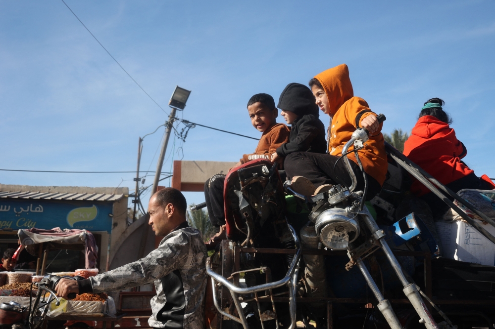 Palestinian children ride in the back of a tuk-tuk in Gaza's southern city of Rafah on January 20, 2025, as residents return following a ceasefire deal a day earlier between Israel and the Palestinian Hamas group. — AFP pic