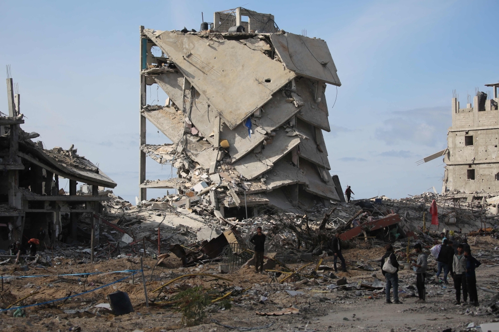 Palestinians stand near building rubble in a ruined neighbourhood of Gaza's southern city of Rafah on January 20, 2025, as residents return following a ceasefire deal a day earlier between Israel and the Palestinian Hamas group. — AFP pic
