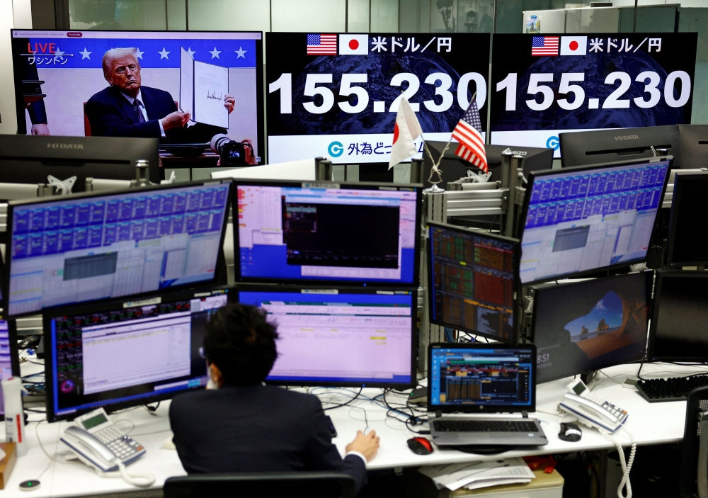 A screen broadcasting live footage of the US President Donald Trump presenting an executive order during the inaugural parade while other screens display the current Japanese Yen exchange rate against the US dollar are seen at a dealing room of the foreign exchange trading company Gaitame.com, in Tokyo, Japan January 21, 2025. — Reuters pic 