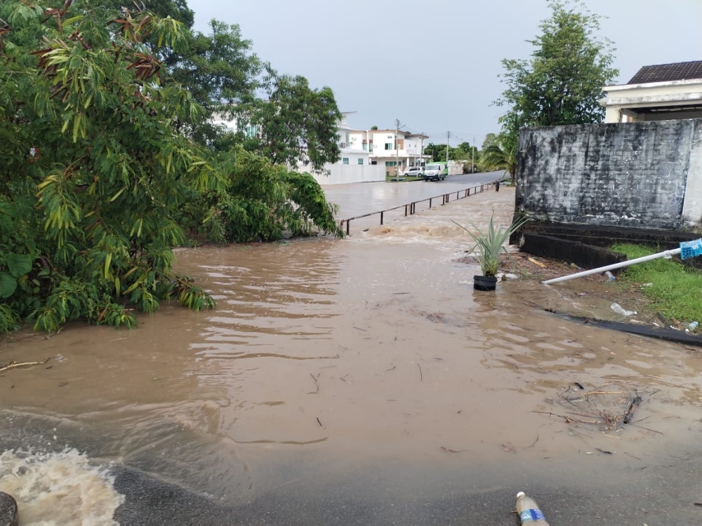 Photo shows water flowing strongly from a storm drain down Jalan Aru. — The Borneo Post pic
