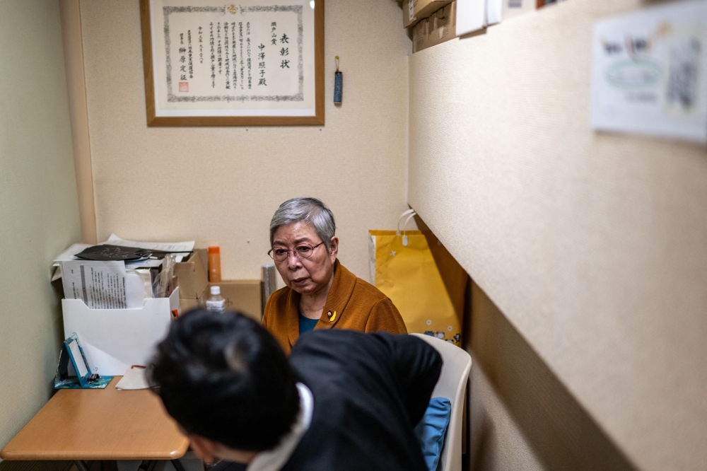 This picture taken on December 14, 2024 shows retired unpaid parole officer ‘hogoshi’ Teruko Nakazawa (back) talking with her former parolee in the smoking room of a cafe in Tokyo. — AFP pic 