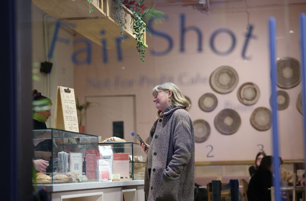Customer Mary Cheshire speaks to a learner at the till, as she waits for her coffee at Fair Shot, a cafe set up to train young people with autism and other learning disabilities in employment skills, in central London, Britain, January 15, 2025. — Reuters pic