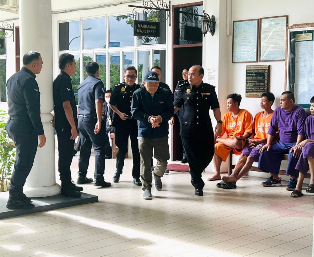 MACC personnel escort the suspect following proceedings at the Bintulu Court Complex. — The Borneo Post pic