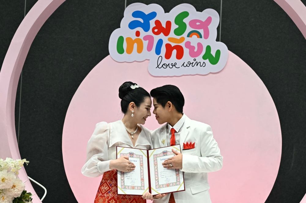 Ploynaplus Chirasukon (left) and Kwanporn Kongpetch pose for pictures after registering their same-sex marriage in Bangkok today. — Pic by AFP