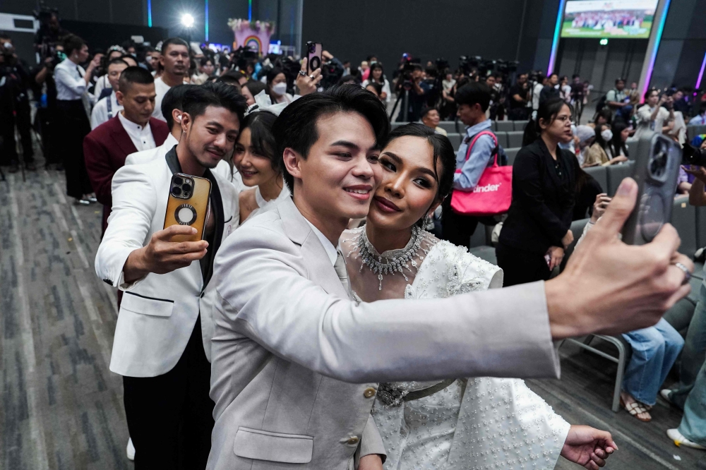 A same-sex couple poses for pictures at a marriage registration event at Paragon shopping mall in Bangkok on January 23, 2025. — AFP pic