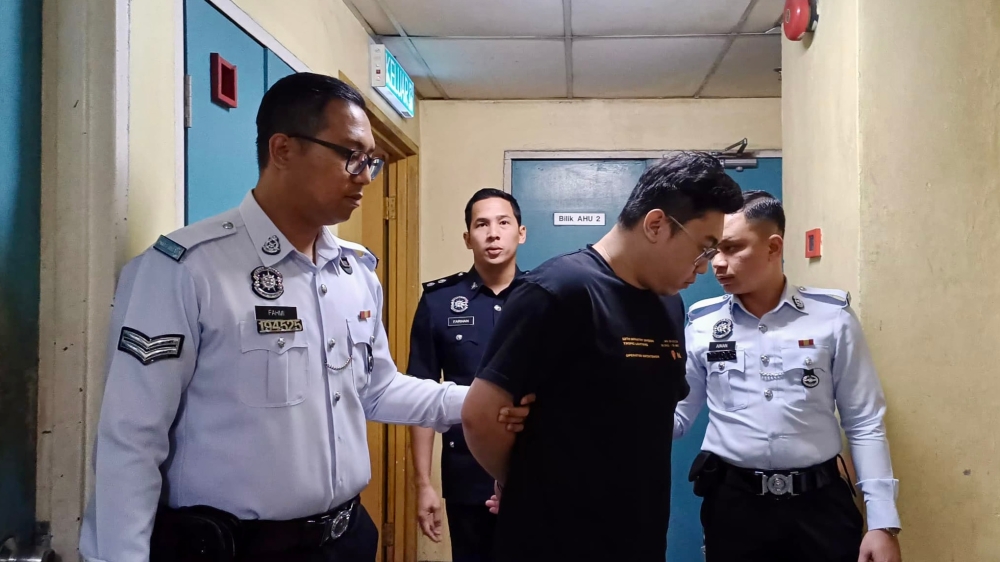 The accused Christopher Lim Ka Hen being escorted by policemen to the Johor Baru Magistrate's Court where he later pleaded guilty for careless and inconsiderate driving that resulted in an accident. Jan 24, 2025 – Picture by Ben Tan