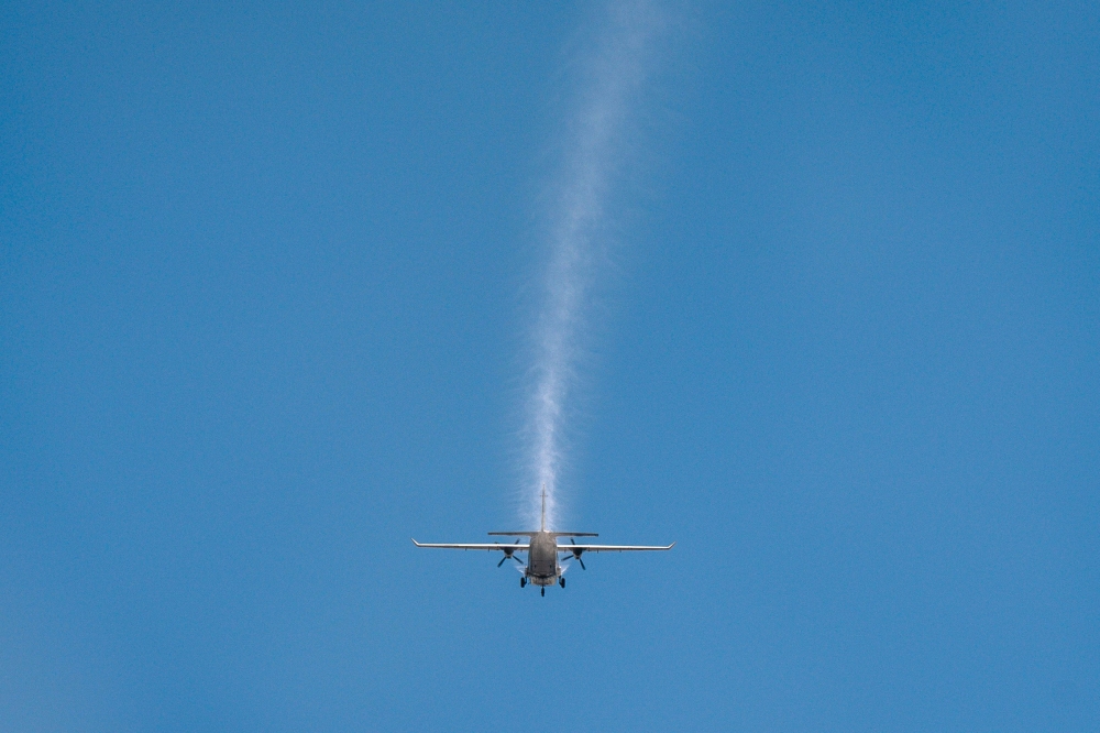 This photo taken on January 15, 2025 shows an aircraft from Thailand's Royal Rainmaking department taking part in an atmospheric modification mission to displace pollution by spraying icy water in the air on the outskirts of Bangkok. Flying some 5,000 feet high through cloudless blue skies, a small aircraft sprays a white mist over a thick haze of pea soup smog below. — AFP pic