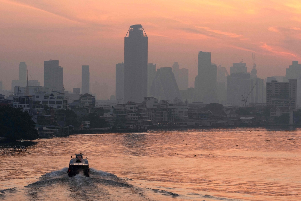 A boat navigates the Chao Phraya river as skyscrapers are seen amid high air pollution levels in Bangkok January 21, 2025. Air pollution in the Thai capital forced the closure of more than 350 schools on January 24, city authorities said, the highest number in five years. — AFP pic