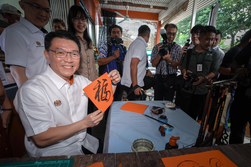 The Minister of Housing and Local Government, Nga Kor Ming, poses after drawing calligraphy during a visit to Canning Market, Ipoh. — Bernama pic