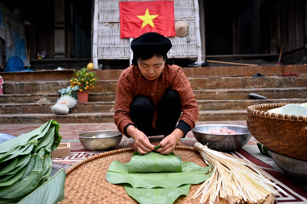 Nguyen Thi Thuy Hong wraps ‘banh chung’ rice cake, a traditional Tet (Vietnamese New Year) delicacy, in the yard of her house on the outskirts of Hanoi. — AFP pic