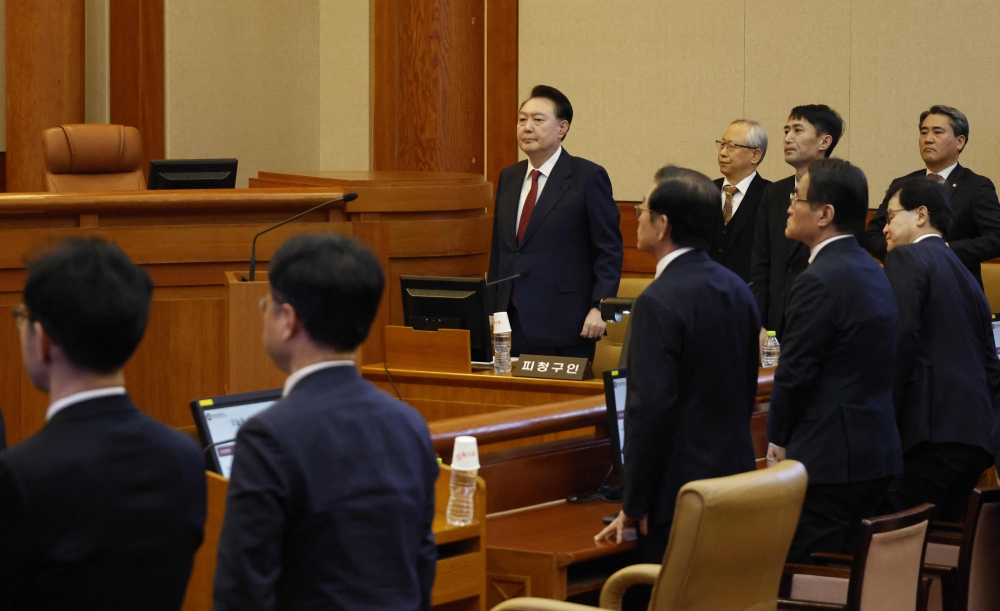 Impeached South Korean President Yoon Suk Yeol (third from left) stands in the Constitutional Court in Seoul on January 23, 2025. — AFP pic