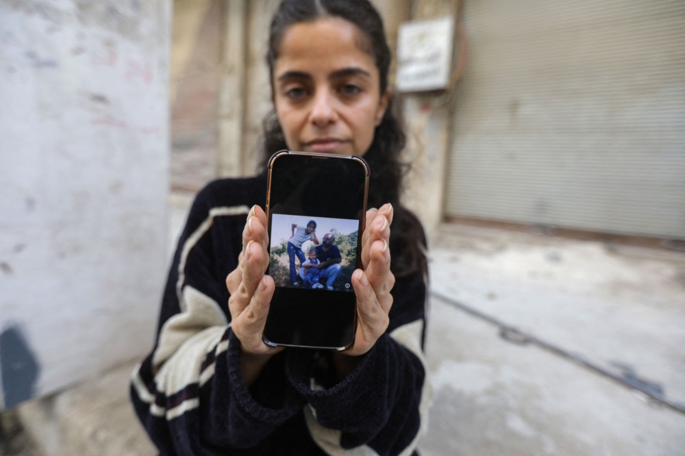 Syrian activist and former refugee Wafa Mustafa shows a picture of her missing father Ali on her phone after attending a demonstration in Damascus. — Pic by AFP