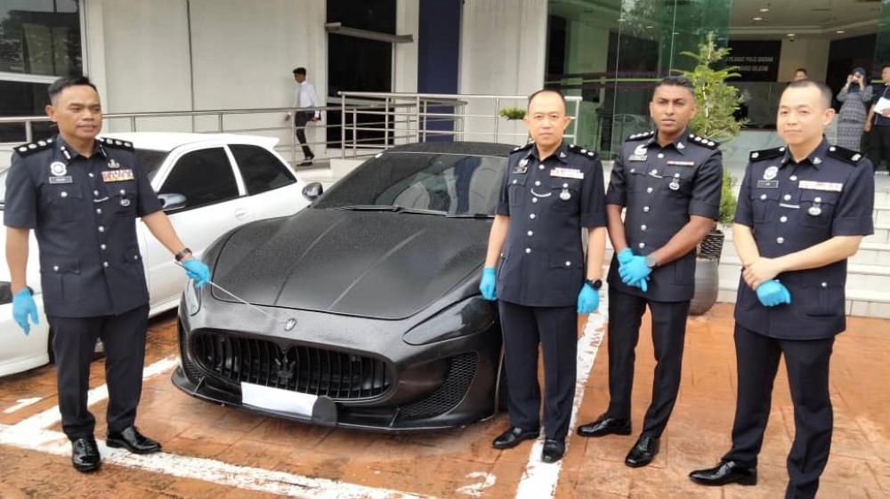 Johor Baru South police chief Assistant Commissioner Raub Selamat (left) and senior police officers with the seized Maserati GranTurismo luxury coupe at the Johor Baru South district police headquarters. — Picture by Ben Tan