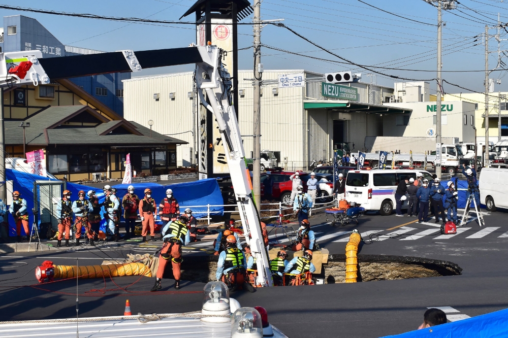Firefighters work to rescue a truck driver after his vehicle was swallowed up by a sinkhole at a prefectural road intersection, in the city of Yashio, Saitama Prefecture on January 28, 2025. — Jiji Press handout pic via AFP 