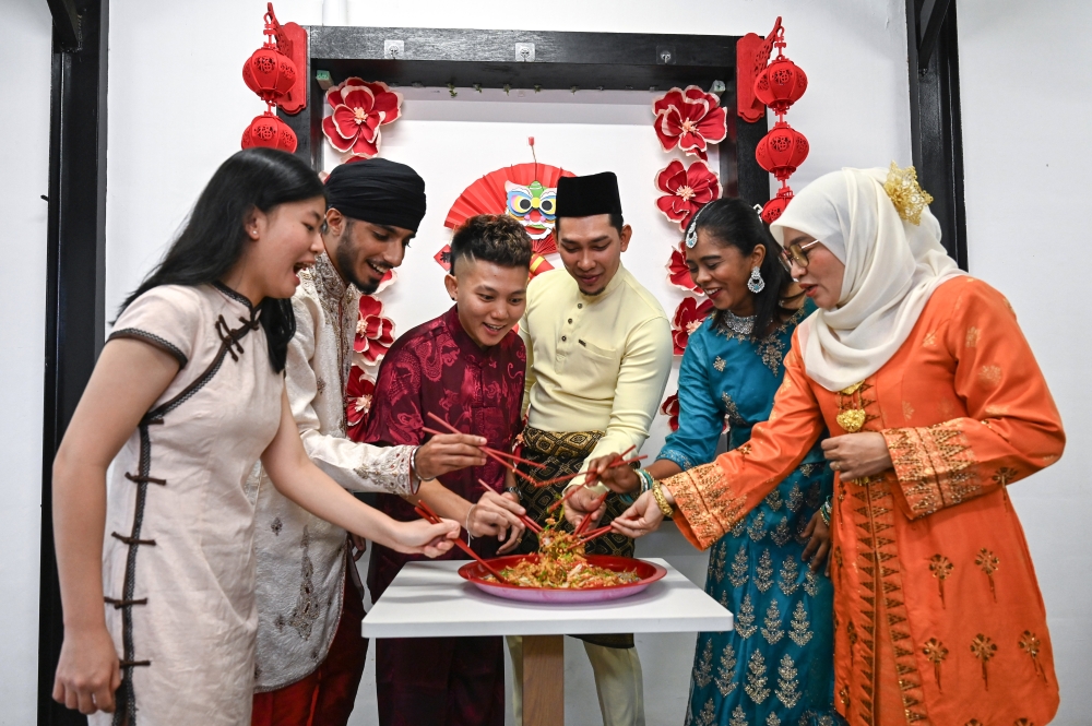 Liaw Yong Sien, 27 (third left), along with five friends of different religions, mixed Yee Sang during a festive meal in celebration of the Chinese New Year in Chinatown, Kuala Terengganu. — Bernama pic