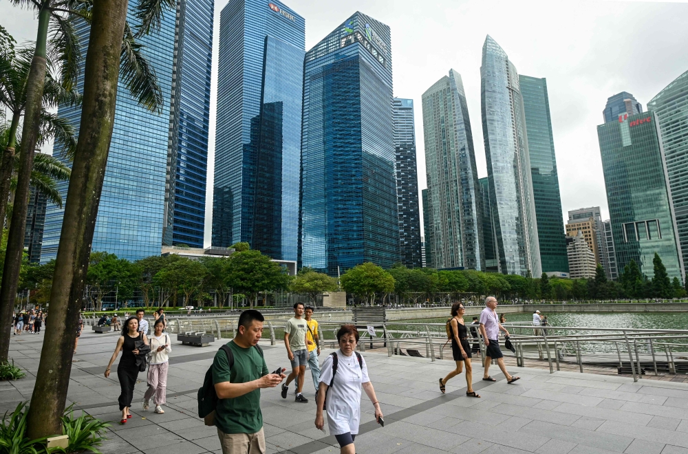 People walk along the promenade at Marina Bay in Singapore on January 27, 2025. Singapore’s luxury condominium resale market has slowed significantly in 2024, with property agents struggling to find buyers despite a high number of listings. — AFP pic 