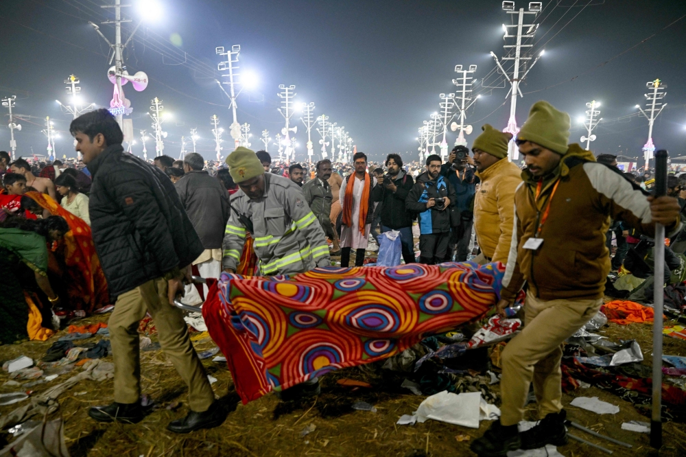 Police personnel carry a victim of stampede on a stretcher, during the Maha Kumbh Mela festival in Prayagraj on January 29, 2025. — AFP pic 