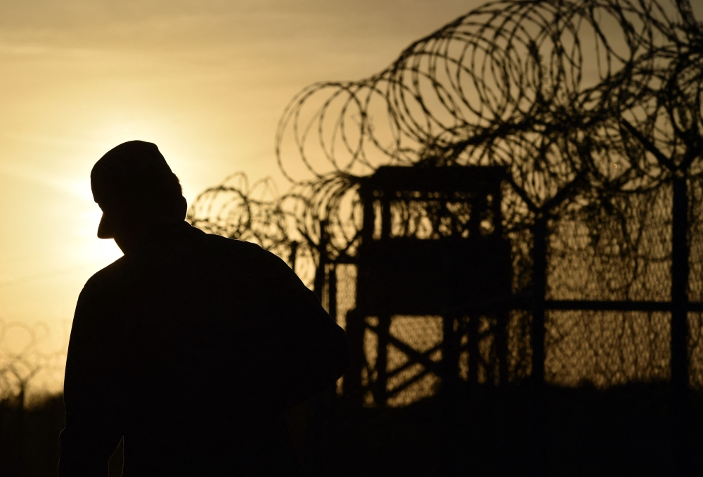 This photo made during an escorted visit and reviewed by the US military, shows an US soldier walking next to the razor wire-topped fence at the abandoned 