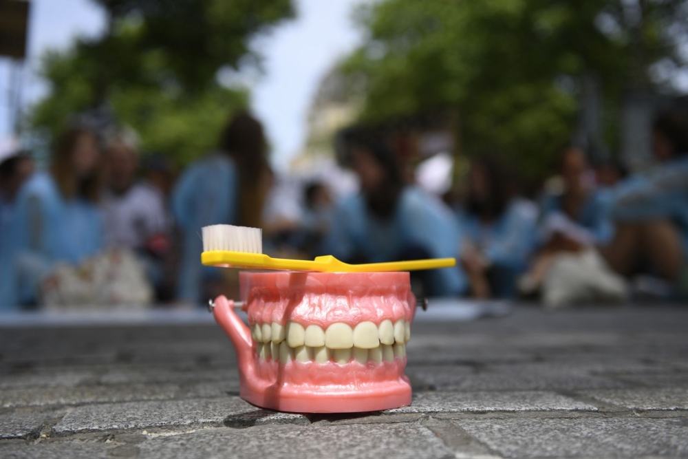 An illustrative photo shows a toothbrush placed atop a set of false teeth. — AFP pic