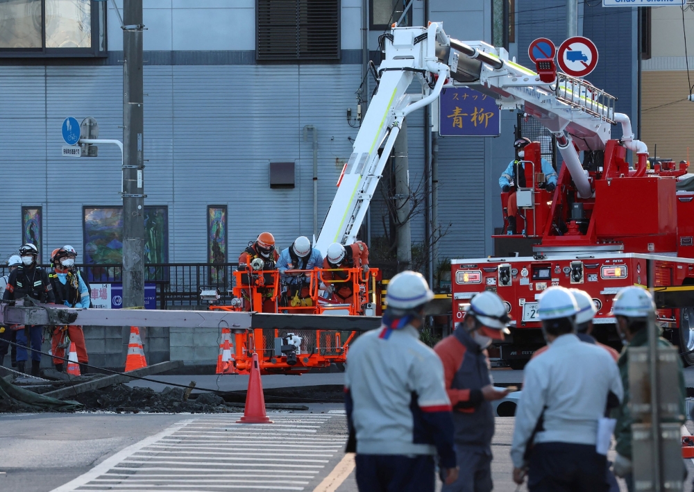 Rescue operations continue for a truck driver after his vehicle was swallowed up by a sinkhole at a prefectural road intersection the day before, in the city of Yashio, Saitama Prefecture on January 29, 2025. — AFP pic