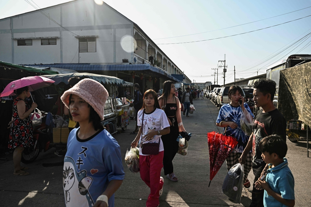 This photo taken on January 26, 2025 shows Myanmar migrant workers walking to an outdoor market in Samut Sakhon. 