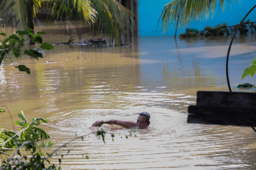 Eddy Sabara Jamaludin, 70, had to swim to shallow waters after inspecting his son’s flood-submerged home during a visit to Kampung Gana Jati, Telupid, Sandakan yesterday. — Bernama pic 