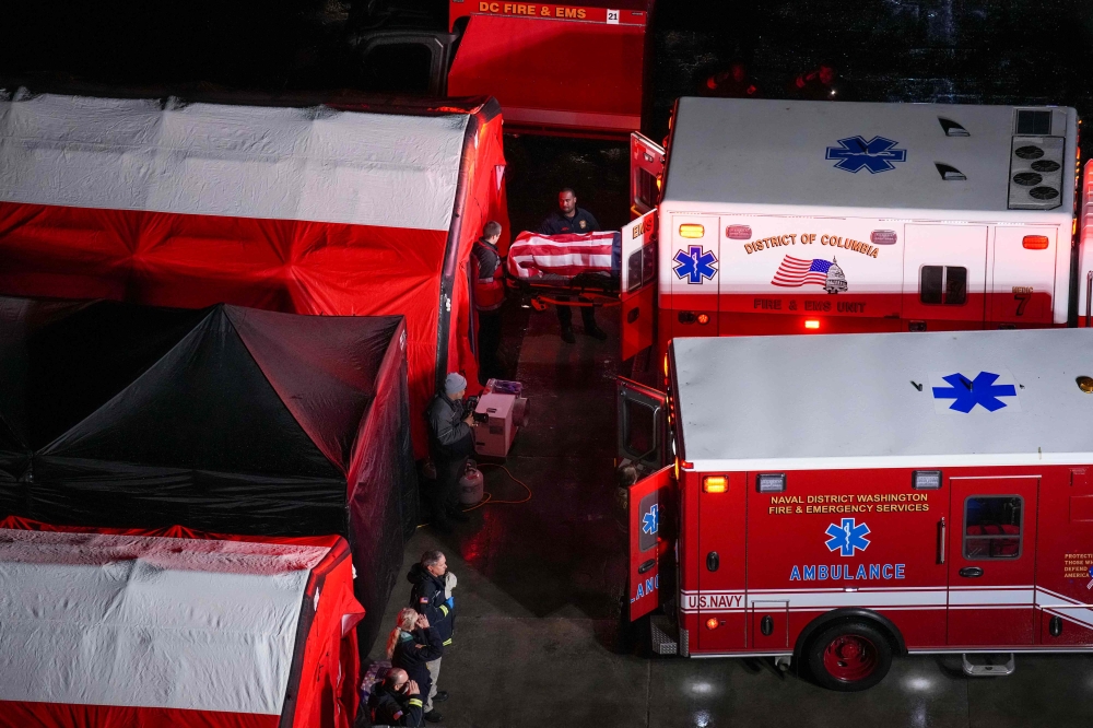 Local first responders salute the flag draped bodies of service members killed in the aviation crash at a temporary emergency disaster site at Buzzards Point.  — Pic by AFP