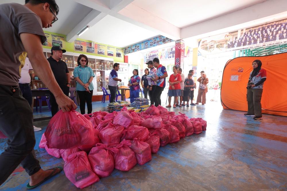 NGO personnel distributed food aid to flood victims at the Temporary Relief Centre (PPS) at SMK Bandau Kota Marudu yesterday. Approximately 300 flood victims are housed at this PPS. — Bernama pic