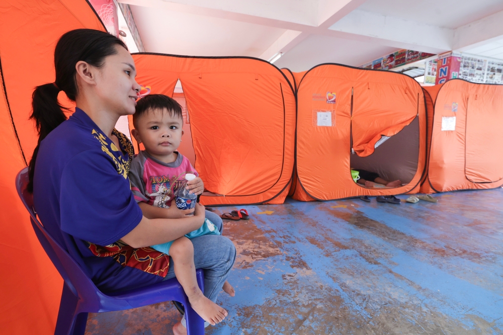 Flood victim Asni Malungka, 31, along with her three-year-old child Jonny Alrica Angela’s, from Kampung Salaping, is among the 300 residents relocated to the SMK Bandau Temporary Relief Centre (PPS) due to flooding. — Bernama pic