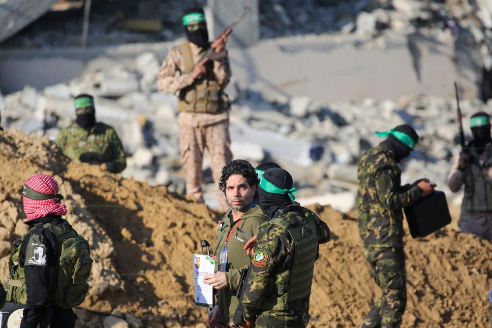 Palestinian militant group Hamas fighters escort Israeli-French hostage Ofer Kalderon before handing him over to a Red Cross team in Khan Yunis on February 1, 2025, as part of fourth hostage-prisoner exchange. — AFP pic