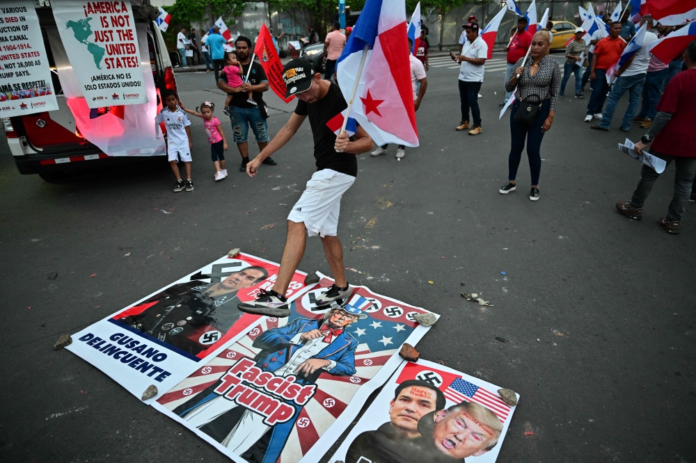 A demonstrator steps on a poster depicting US Secretary of State Marco Rubio and US President Donald Trump as he takes part in a protest against the visit of Rubio in Panama City. — AFP