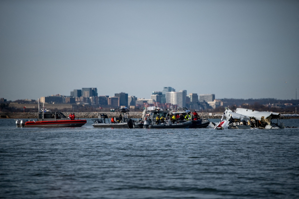 US Coast Guard, along with other search and rescue teams, operate near debris at the crash site in the Potomac River in a location given as Washington. — Pic by Reuters