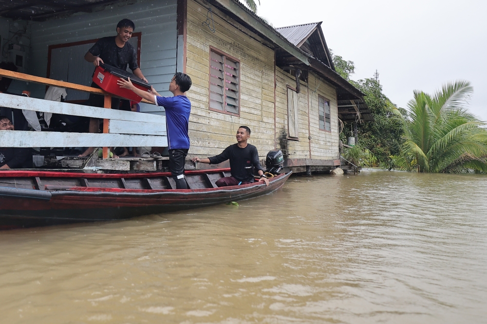Volunteers distribute food aid to Kampung Hulu Serian villagers trapped by floods. — Bernama pic