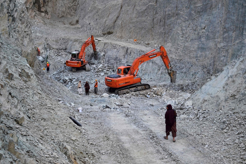 Afghan workers standing beside excavators at a Nephrite mine in the mountains of Goshta district, Nangarhar province. — AFP pic