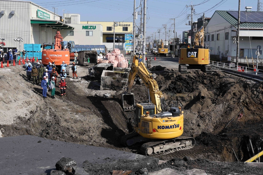 Excavators and rescue personnel working to construct a slope for rescue operations at the site where a truck on January 28 plunged into a sinkhole, trapping the vehicle's driver, in Yashio, Saitama Prefecture on February 1. — AFP pic