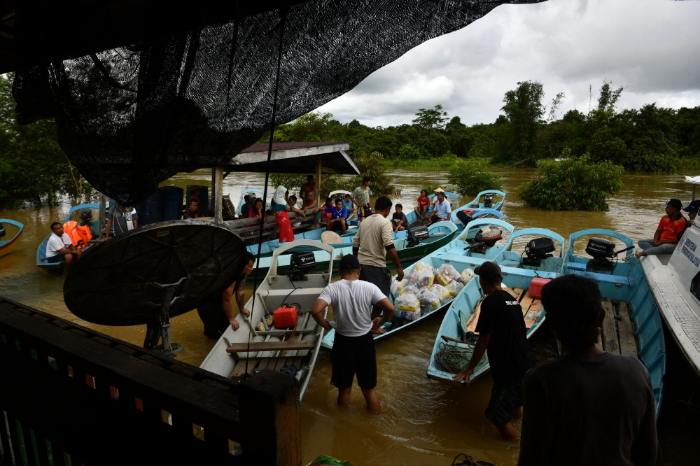 Volunteers unload food packages and essential items from a boat to be given to flood evacuees at Rumah Panjang Mulo Sungai Kakus in Tatau, which has been cut off from food supplies since the land routes were submerged on January 18, 2025. — Bernama pic