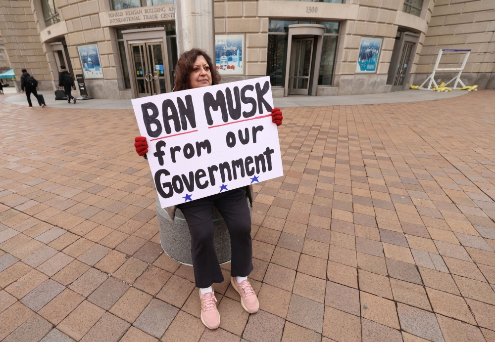 A woman protests against Elon Musk outside the U.S. Agency for International Development (USAID) building after billionaire Musk, who is heading U.S. President Donald Trump's drive to shrink the federal government, said work is underway to shut down the foreign aid agency, in Washington, US. — Pic via Reuters