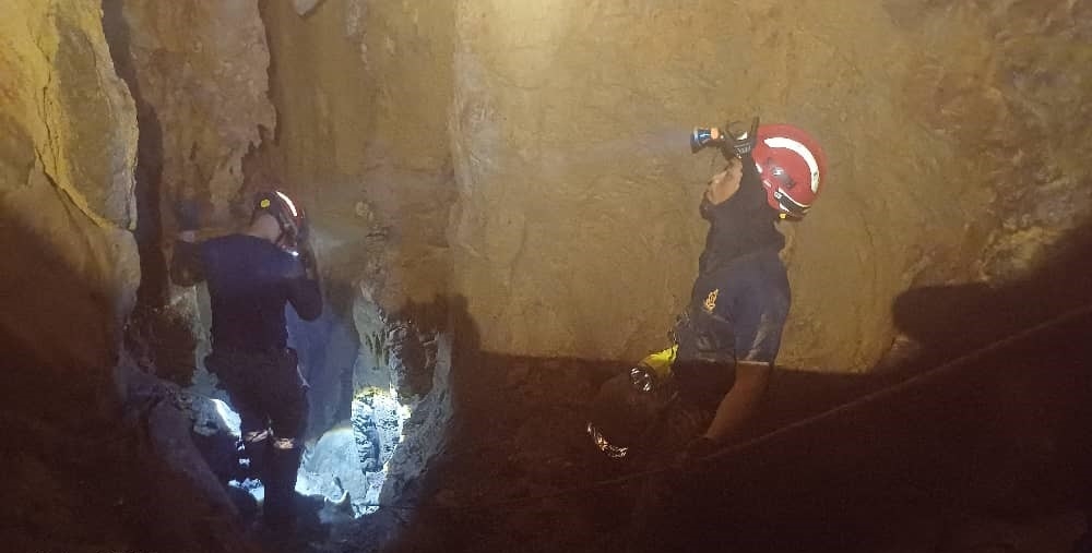 Firefighters attempting to get a closer look inside the narrow cave in effort to retrieve the body of Randy. — The Borneo Post pic