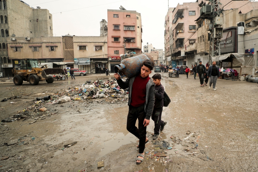 A Palestinian carries a cooking gas cylinder, amid a ceasefire between Hamas and Israel, in Gaza City, February 3, 2025. — Reuters pic