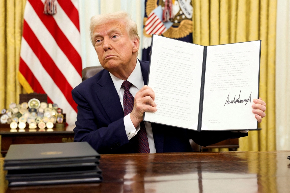 US President Donald Trump holds a signed executive order at the White House, in Washington, US, January 23, 2025. — Reuters pic