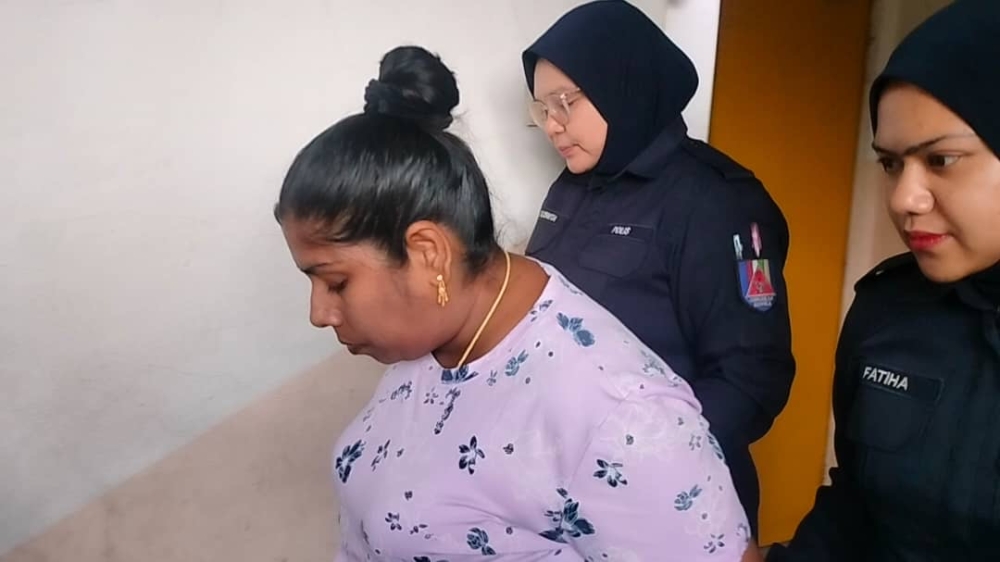 Police officers escorting accused K. Mageswari after she was fined by the Johor Baru Session’s Court together with her boyfriend R. Thayalan for negligence and abuse. — Picture by Ben Tan