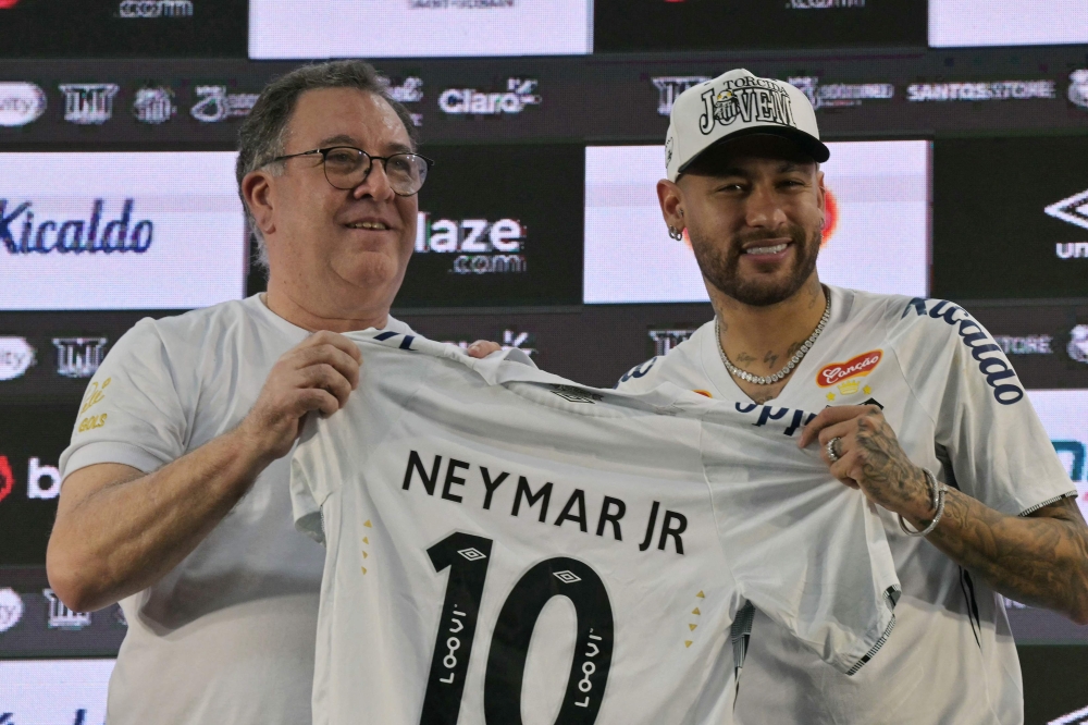 Brazilian football star Neymar (right) and the President of Santos, Marcelo Pirilo Teixeira, display a jersey during his presentation as a new player of the Santos football team at the Urbano Caldeira Stadium in Santos, Sao Paulo state, Brazil on January 31, 2025. — AFP pic