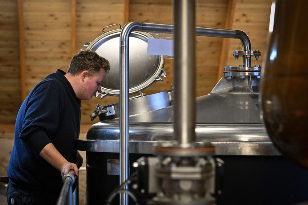 Employee Torran Mealand monitors the production process in the still room at the Nc'nean whisky distillery is pictured in Drimnin, in the western highlands of Scotland on February 3, 2025. — AFP pic