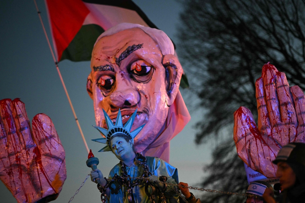 An activist dressed as the Statue of Liberty is pulled in shackles near a large effigy of Israeli Prime Minister Benjamin Netanyahu as they rally in support of Palestinians during the 