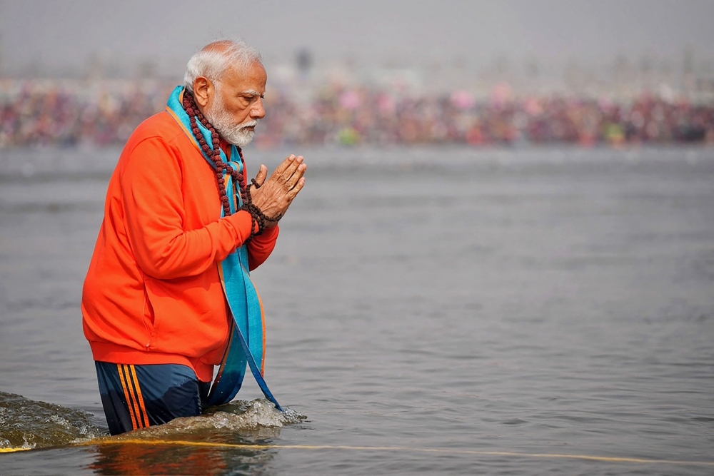 This handout photograph taken on February 5, 2025 and released by the Indian Press Information Bureau (PIB) shows India's Prime Minister Narendra Modi offering prayers before taking a holy dip in the sacred waters of Sangam, the confluence of Ganges, Yamuna and mythical Saraswati rivers during Maha Kumbh Mela festival, in Prayagraj.