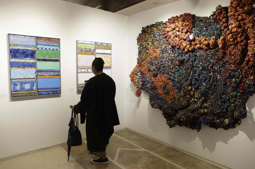 A visitor walks past artworks by Ethiopian artist Tegene Kunbi and Nigerian artist Samuel Nnorom during the 1-54 Marrakesh contemporary African art fair on January 30, 2025. — AFP pic