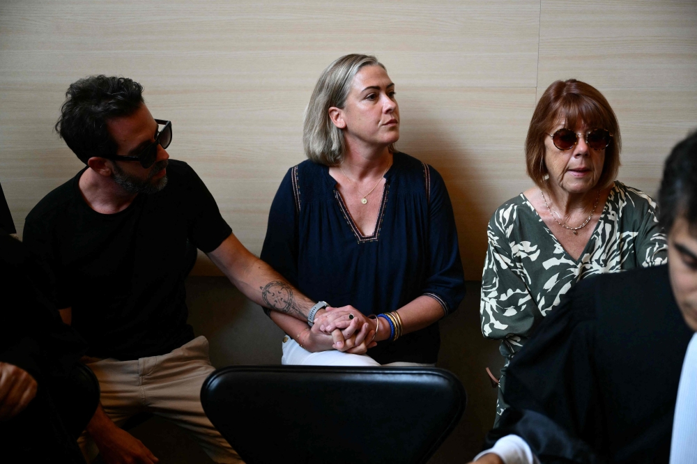 Gisele P. (right) sits beside her daughter Caroline Darian (centre) and her son (left) at the courthouse during the trial of her husband accused of drugging her for nearly ten years and inviting strangers to rape her at their home. — AFP pic