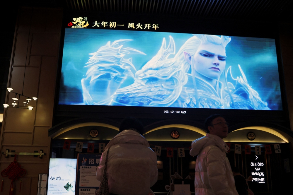 People stand near a giant screen showing a trailer for the Chinese movie ‘Nezha 2’, at a cinema in Beijing February 6, 2025. — Reuters pic  