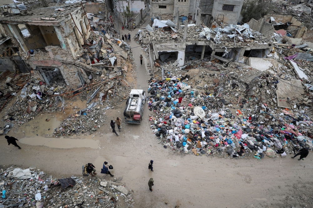 Palestinians walk past the rubble of buildings destroyed during the Israeli offensive, on a rainy day, amid a ceasefire between Israel and Hamas, in Gaza City February 6, 2025. — Reuters pic